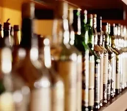 A long row of wine and spirit bottles on a dimly lit shelf.