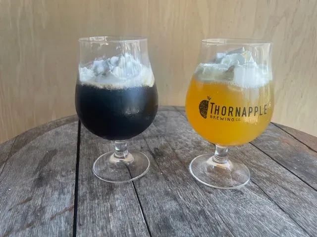 Dark and amber stemmed drinks with whipped cream on wood.