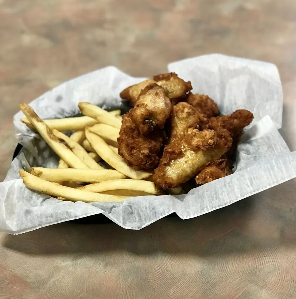 Golden-brown fried chicken and french fries in a black serving basket.