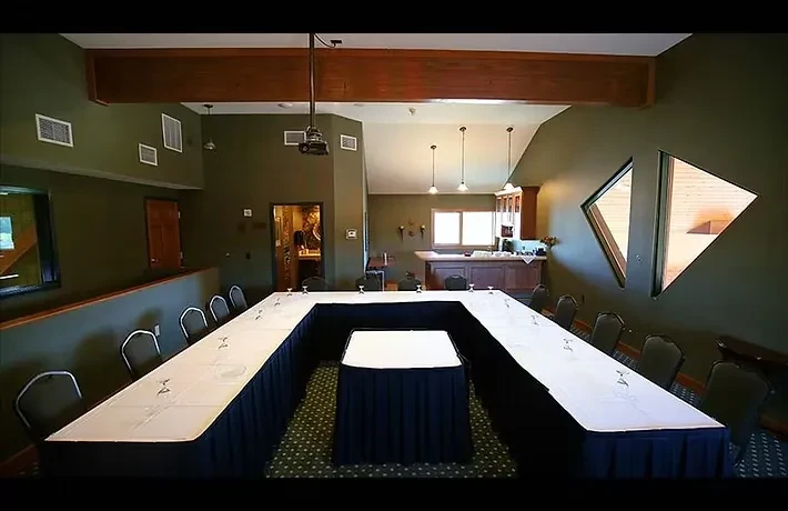 Formal event room with U-shaped table, bar, and green walls.
