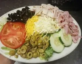 Colorful chef's salad with ham, turkey, olives, tomato, cucumber, cheese.