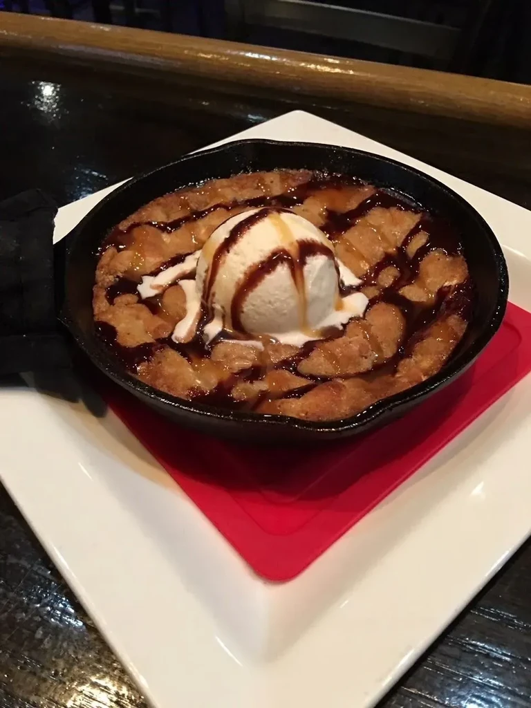 Warm brownie skillet topped with melting vanilla ice cream and sauces.