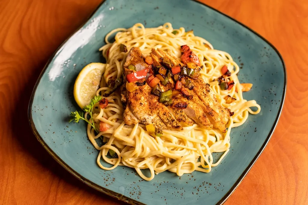 Creamy spaghetti with sliced grilled chicken, bell peppers, lemon, parsley.