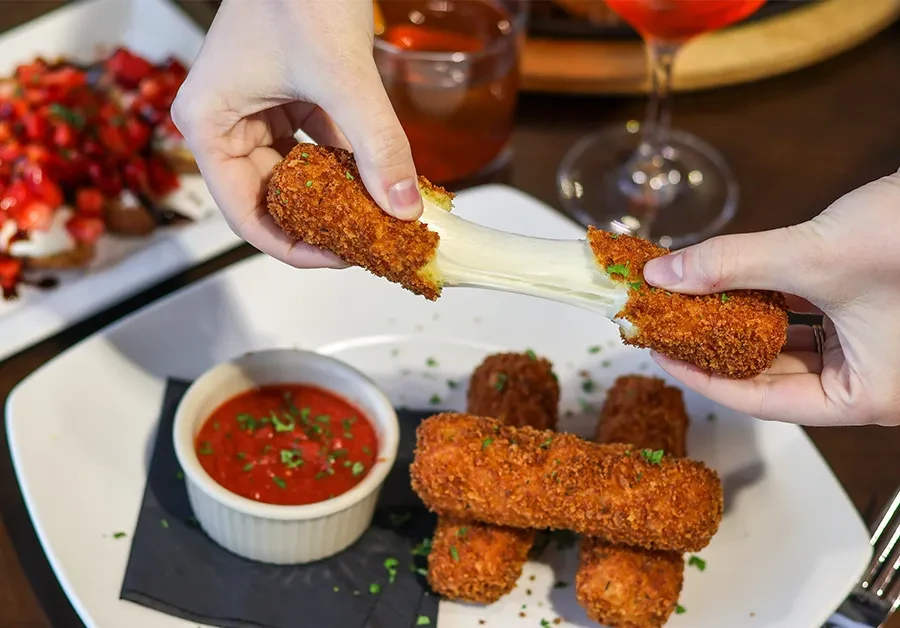 Hands pulling fried cheese apart, revealing a long, stretchy cheese pull.