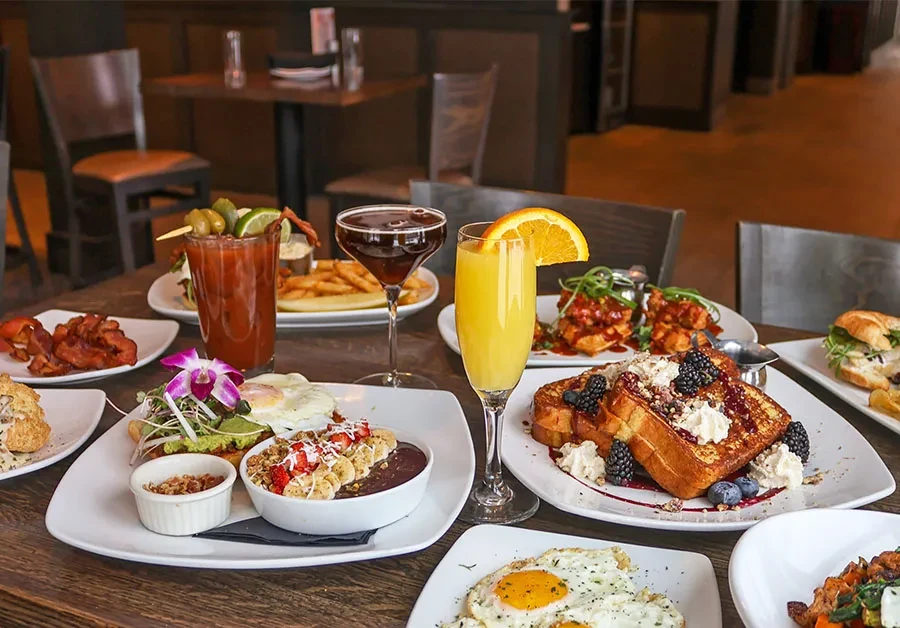 A brunch spread with French toast, eggs, waffles, and drinks.