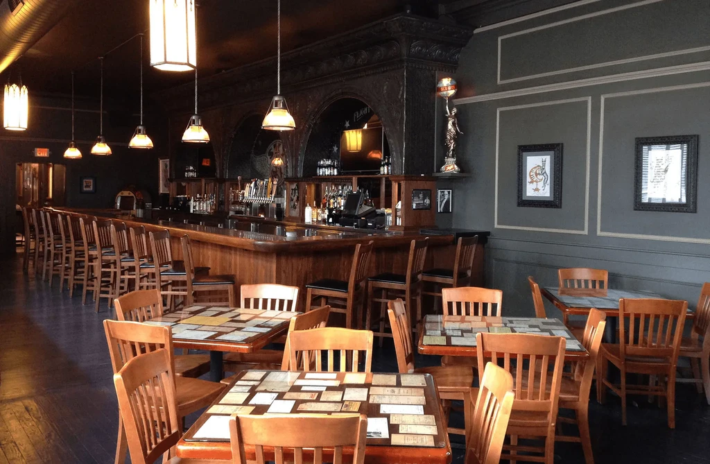 Ornate restaurant interior with a long bar, dining tables, and unique tabletops.
