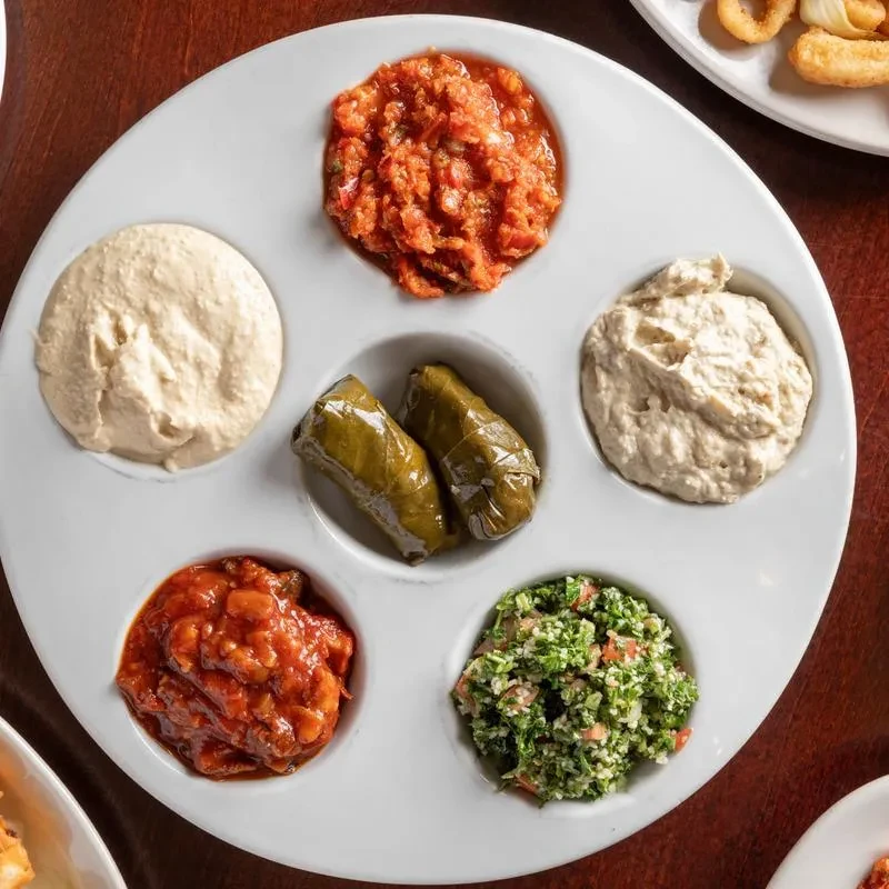 Overhead circular platter with Mediterranean dips, salads, and dolmas.