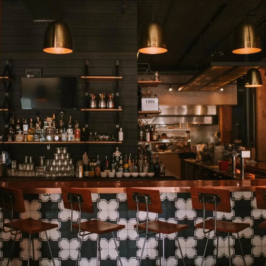 Stylish bar with copper top, geometric tiles, and liquor shelves.
