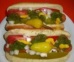 Stacked hot dogs with onions, tomatoes, relish, mustard, peppers, and pickle.