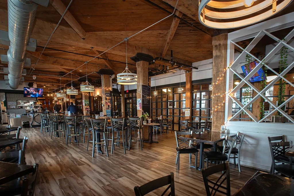 Modern industrial restaurant interior featuring exposed beams, pendant lights, and bar.