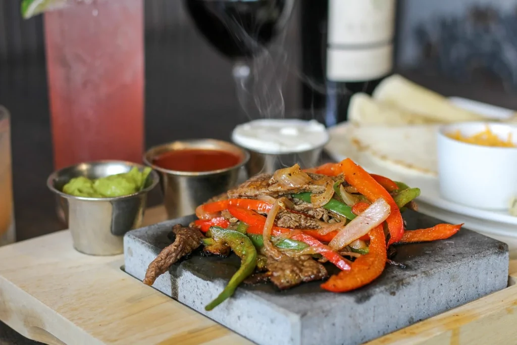 Sizzling chicken or steak fajitas with peppers, guacamole, and sour cream.