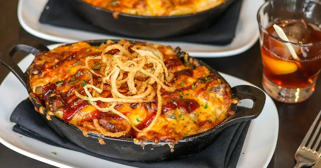 Bubbly cheesy pasta in skillet with crispy onions and red sauce.