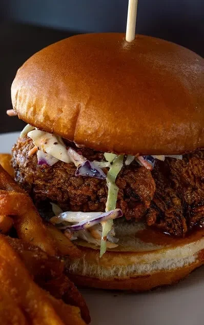 Crispy fried chicken sandwich with coleslaw, brioche bun, and waffle fries.
