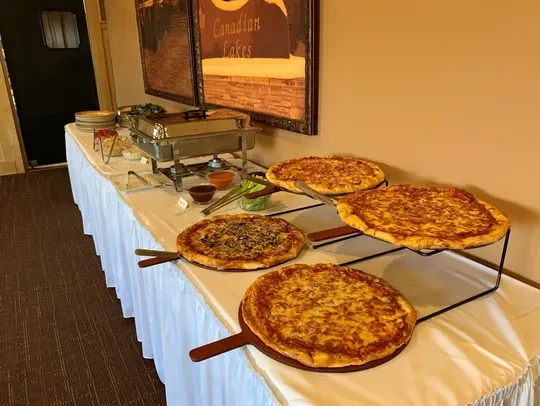 Indoor buffet setup with pizzas, salads, and other food items.