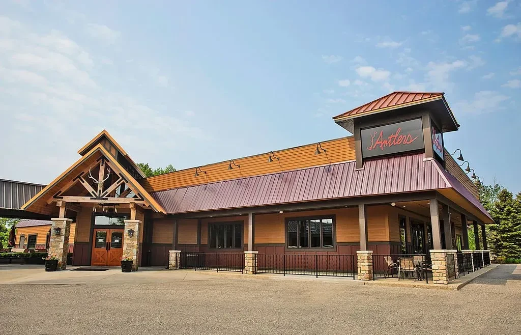 Exterior of rustic lodge-style Antlers restaurant, featuring wood, stone, and antlers.