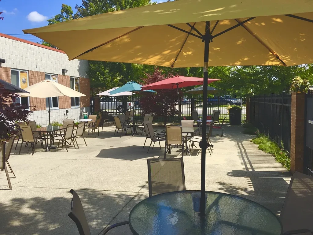 Sunny outdoor cafe patio with many colorful umbrellas, tables, and chairs.