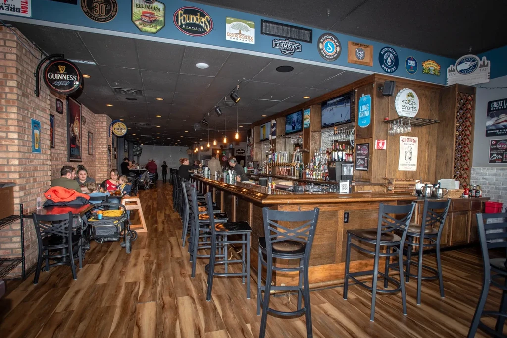 Lively casual bar with patrons, beer taps, sports TVs, and dining.