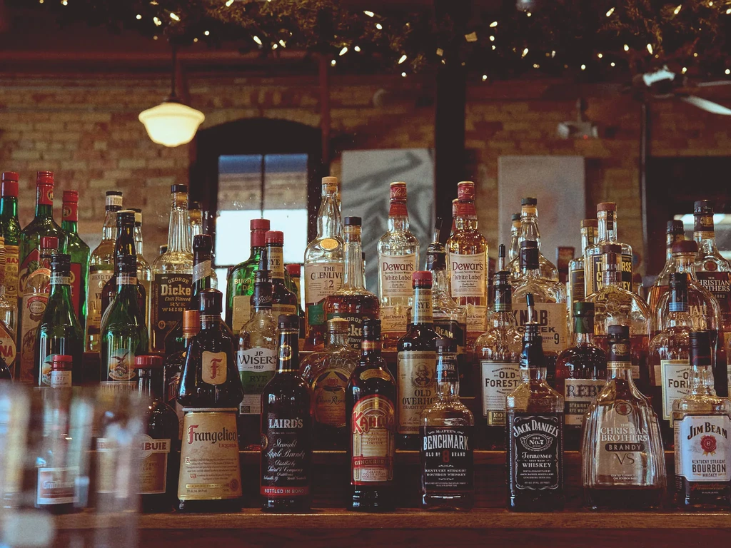 Well-stocked bar counter with numerous bottles of alcoholic spirits.