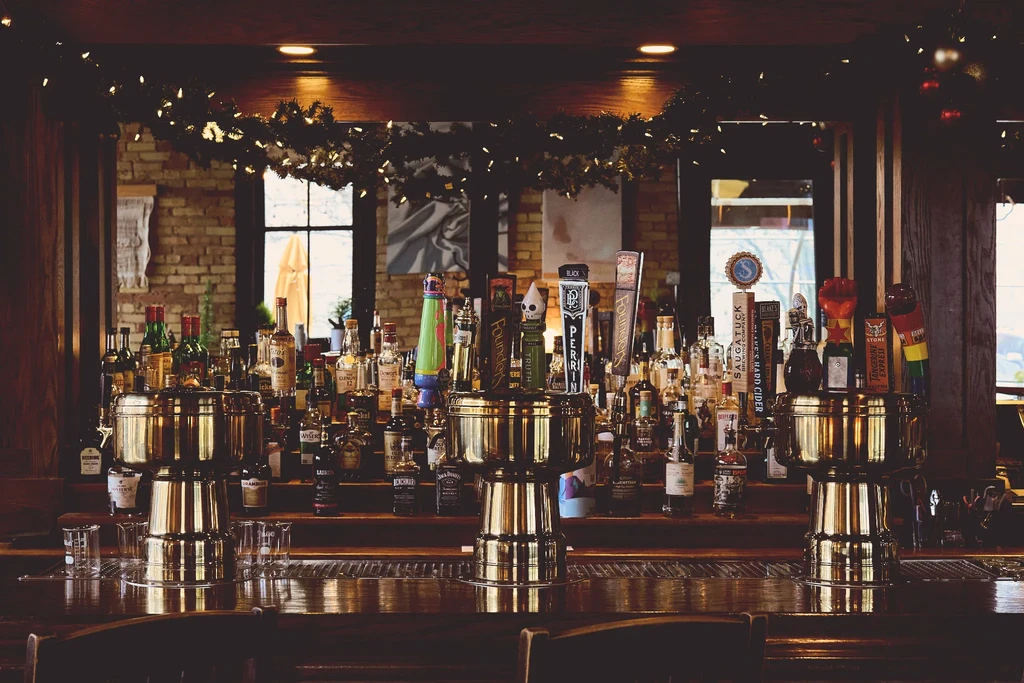 Bar counter with liquor bottles, brass beer taps, and empty glasses.
