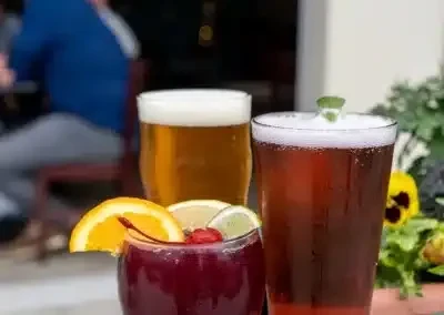 Three beverages: a red cocktail, amber beer, and a mint-garnished drink.