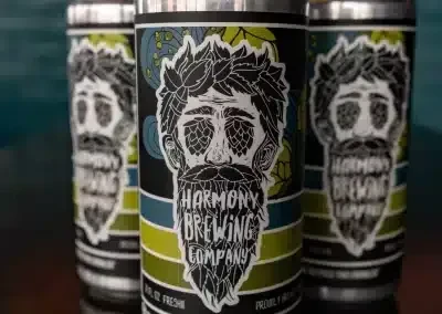 Three Harmony Brewing Company beer cans with stylized man's head labels.