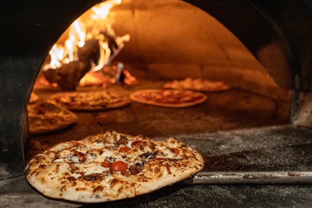 Freshly baked pizza in a glowing wood-fired oven.