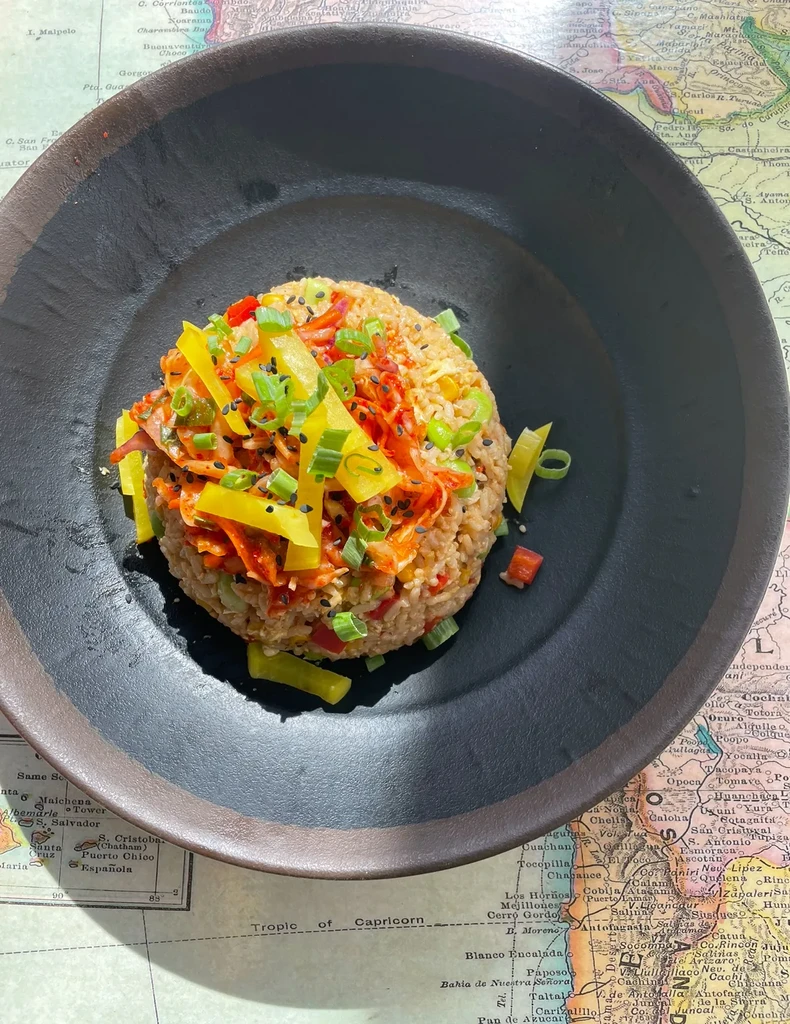 Colorful rice bowl with vegetables and sesame seeds on a faded map.