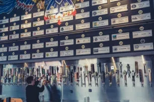 Person operating a tap at a bar with many beer labels.