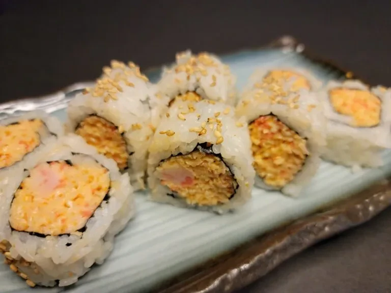 Uramaki sushi rolls with creamy and crispy fillings on a teal dish.