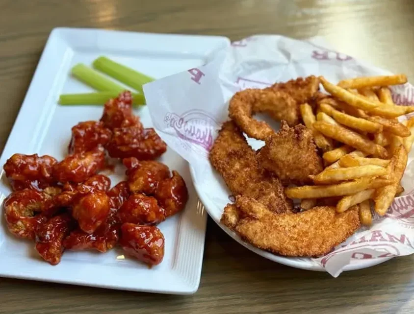 Buffalo chicken wings with celery and chicken tenders with fries.