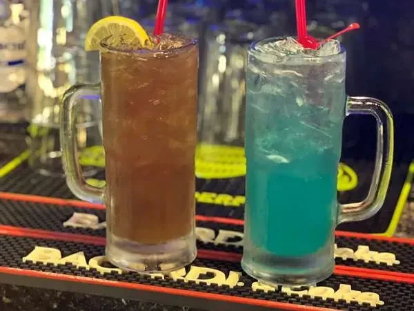 Two iced brown and blue-green cocktails on a Bacardi mat.