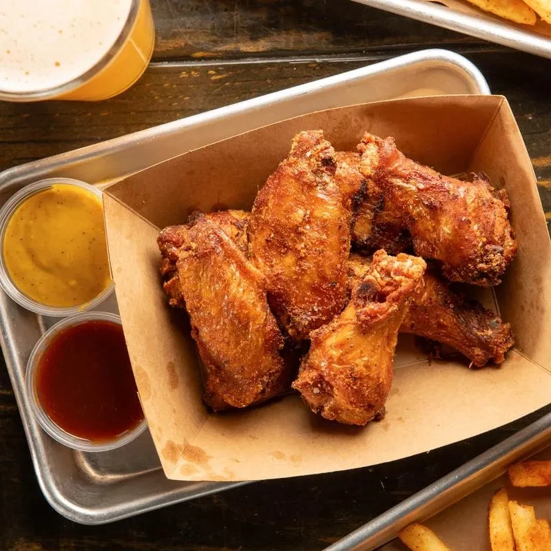 Crispy fried chicken wings with two dipping sauces, beer, and fries.