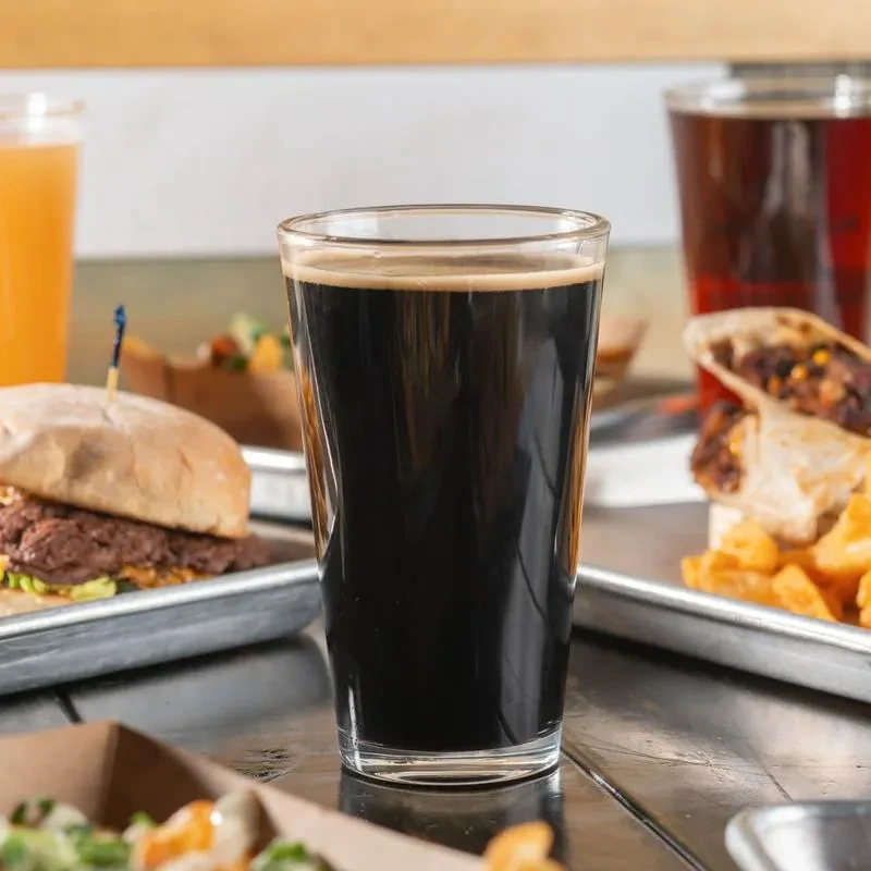 Dark foamy drink, burger, burrito, and fries on a restaurant table.