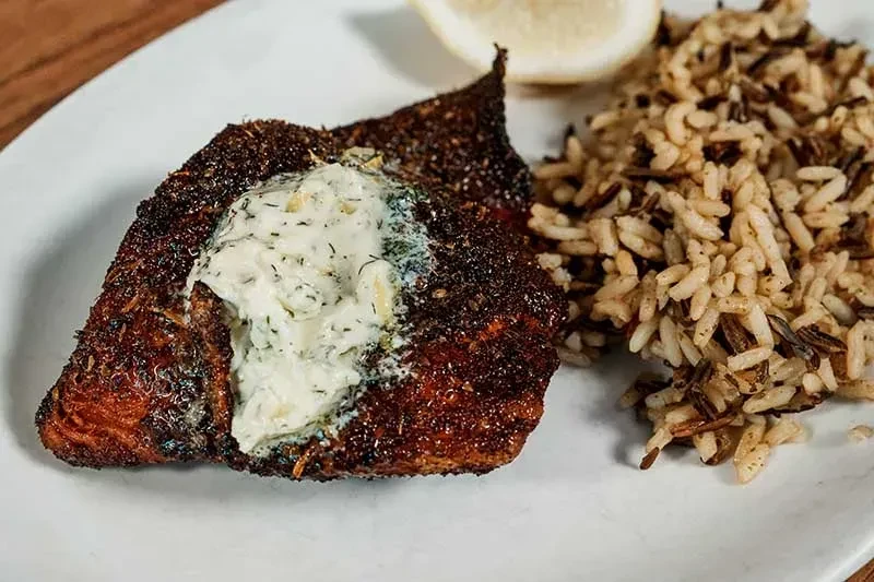 Pan-seared fish topped with creamy sauce, mixed rice, and lemon.