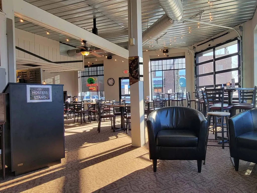 Empty, well-lit modern restaurant with industrial ceiling and varied seating.