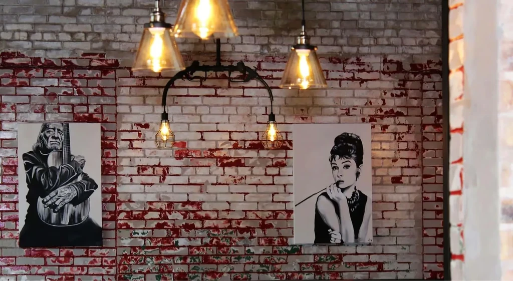 Restaurant interior: Edison bulbs, white-washed brick, Willie Nelson, Audrey Hepburn portraits.