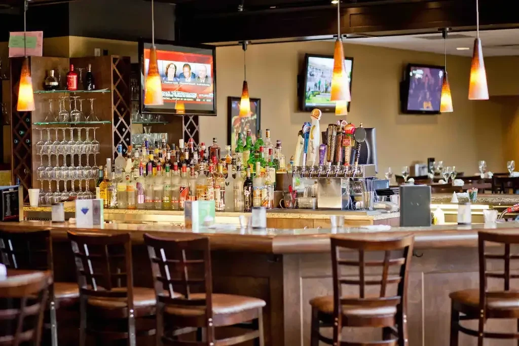 Empty modern bar featuring extensive liquor, beer taps, glassware, and TVs.