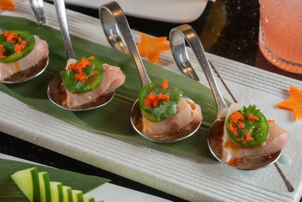 Four elegant spoons of whitefish appetizers with jalapeño, roe, and herb.