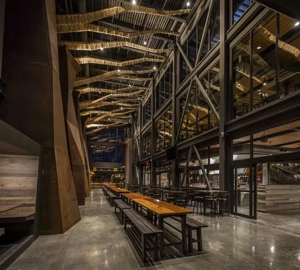 Modern industrial-chic restaurant interior with high ceilings and woven light fixtures.