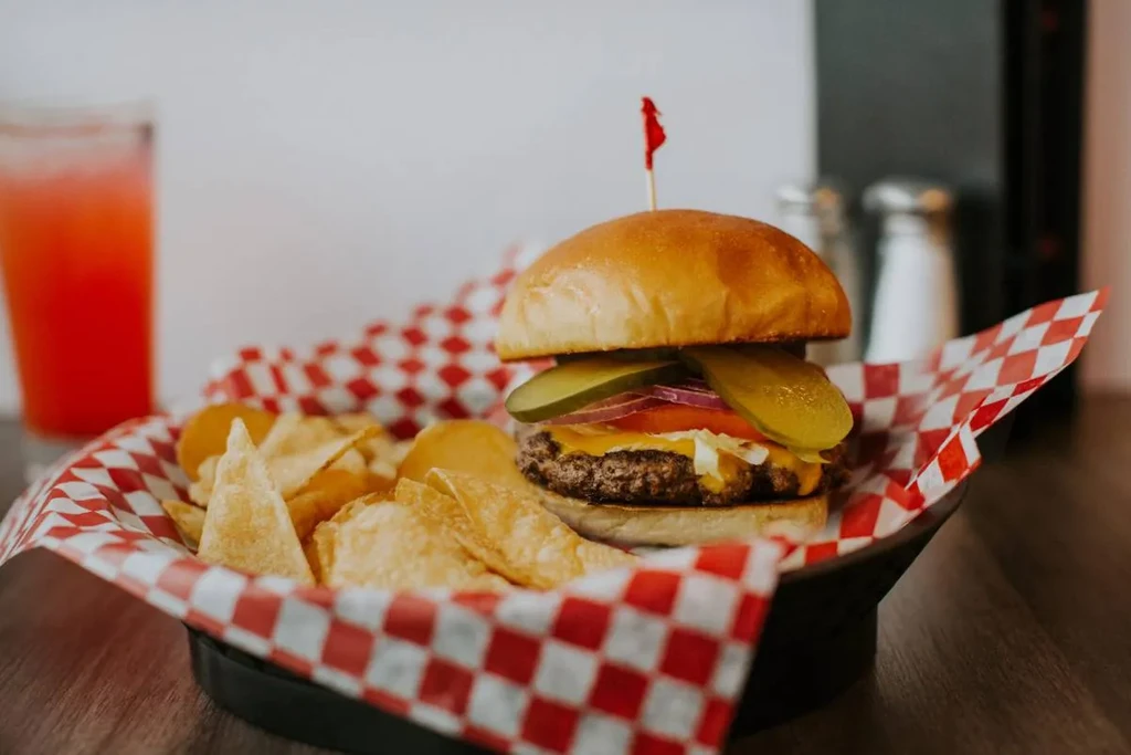 A classic cheeseburger with chips in a checkered paper-lined basket.