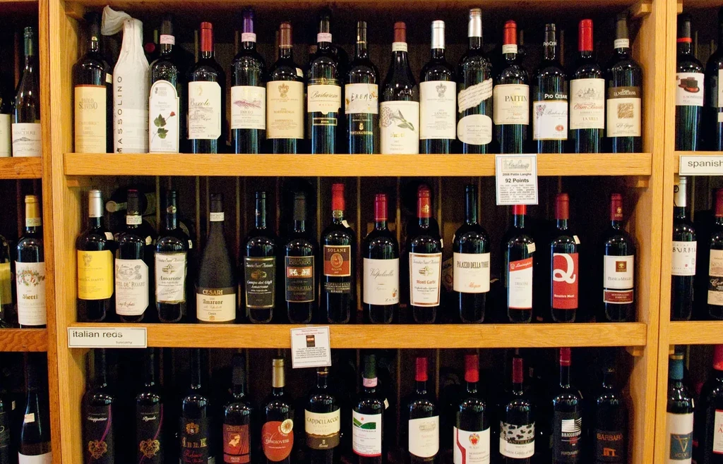 Well-stocked wooden shelves of various wine bottles with tags.