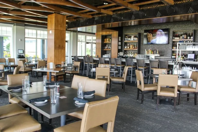 Unoccupied modern restaurant interior with dining area and full bar.