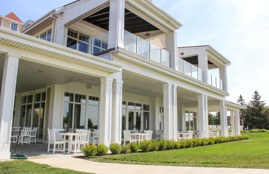 Elegant colonial-style building with outdoor dining patio and green lawn.