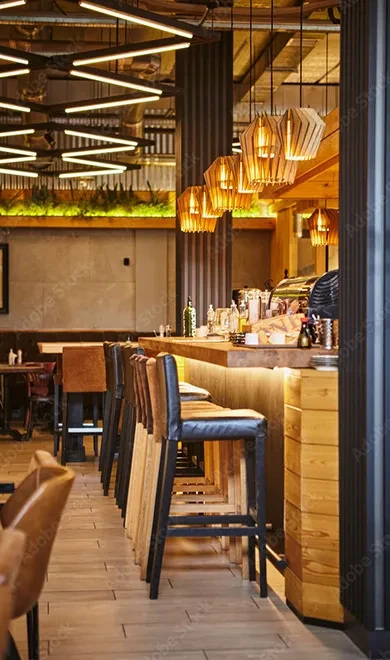Empty modern bar counter with stools, bottles, and geometric pendant lights.