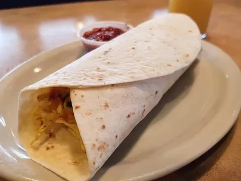 Breakfast burrito with eggs, cheese, salsa, and orange juice.