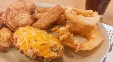 Plate with cheddar twice-baked potato, onion rings, and mixed fried items.