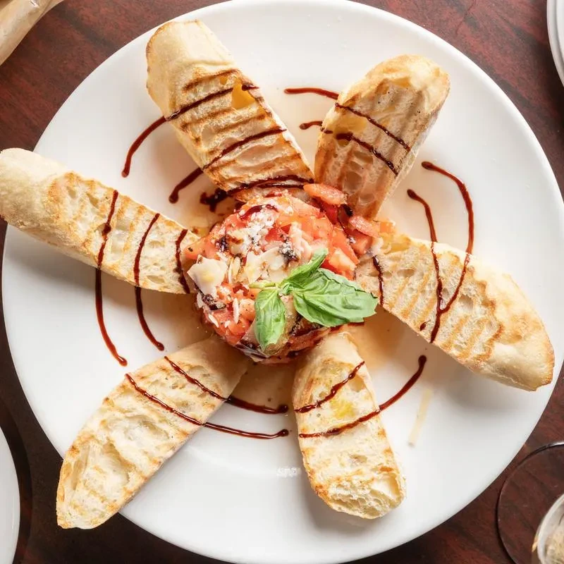 Tomato and basil appetizer with grilled baguette and balsamic glaze.