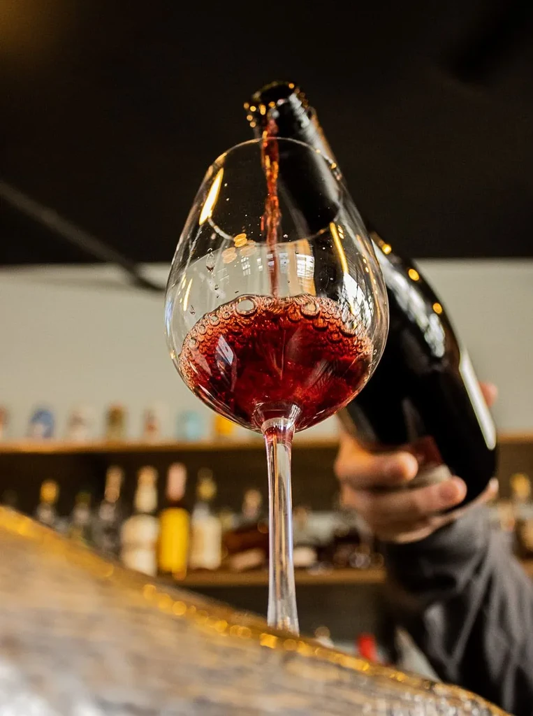Close-up of red wine pouring into a clear stemmed glass.