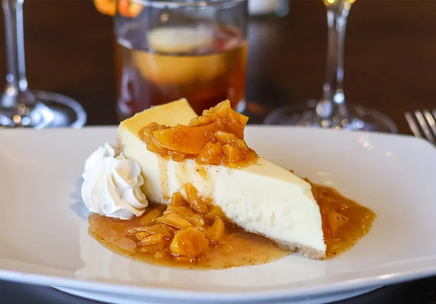 Slice of cheesecake topped with fruit compote and whipped cream.