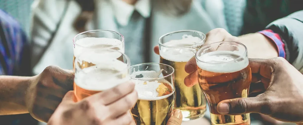 Close-up of five diverse hands clinking beer glasses in a toast.